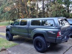 the truck is parked on the side of the road in front of some trees and grass