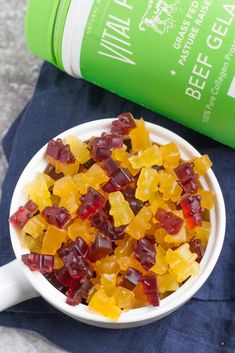 a white bowl filled with gummy bears next to a green bottle and blue towel