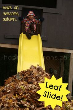 a child sliding down a yellow slide with leaves on the ground in front of it