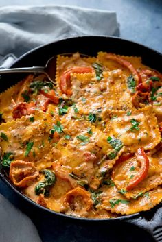 a skillet filled with pasta covered in cheese and tomato sauce, topped with parsley