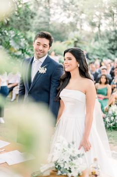 a bride and groom smile as they walk down the aisle at their outdoor wedding ceremony