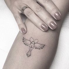 a woman's arm with a small bird tattoo on it