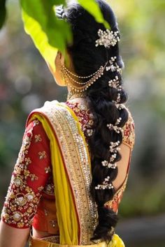 a woman with long hair wearing a yellow and red sari, looking off to the side