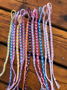 several different colored braids are lined up on a wooden surface