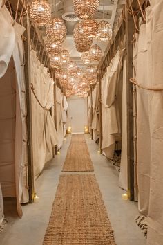 a long narrow hallway with lots of curtains and lights hanging from it's ceiling