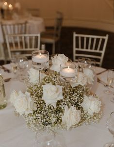 a table with white flowers and candles on it