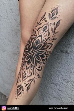 a woman's leg with tattoos on it and an intricate flower design in black ink