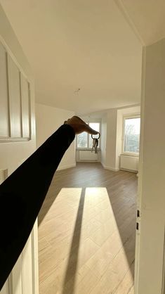 a person is holding their hand out to the camera in an empty room with wooden floors