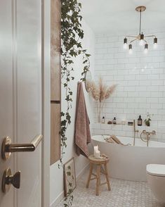 a bathroom with a toilet, bathtub and plant growing on the wall next to it