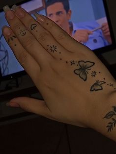 a woman's hand with tattoos on it and a television in the background,