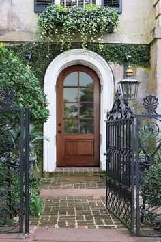 an entrance to a house with a wooden door and wrought iron fenced in gate