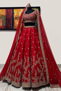 a red lehenga on display in front of a painting