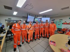 a group of men in orange uniforms standing next to each other on a tile floor