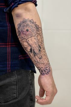 a man's arm with an elephant and flower tattoo on the left side of his arm