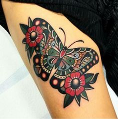 a butterfly tattoo on the thigh with red flowers and green leaves around it's wings