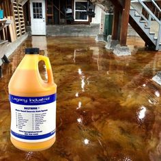 a gallon of liquid sitting on top of a floor in front of a stair case