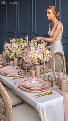 a woman setting a table with pink and white flowers