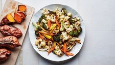 a white plate topped with carrots and cauliflower next to a cutting board