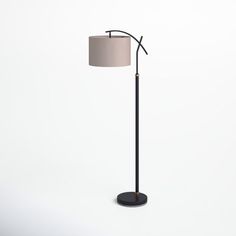 a black floor lamp with a beige shade on it's side and a white background