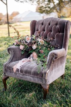 an old chair with flowers on it sitting in the grass