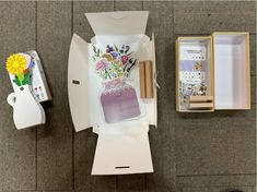 an open box with flowers in it next to a cell phone and some other items