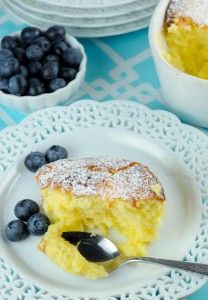 a piece of cake on a plate with blueberries and powdered sugar next to it