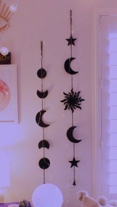 three black and white sun, moon and stars mobiles hanging on the wall in a bedroom