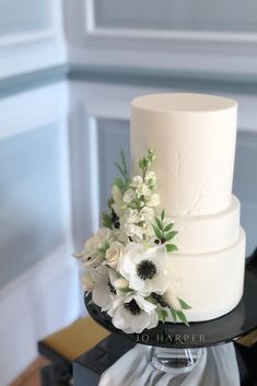 a three tiered white wedding cake with flowers on top