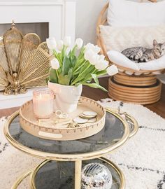 a cat laying on top of a table next to a vase filled with white flowers