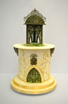 an ornate white and gold clock tower with statues on it's sides, in front of a gray background