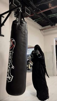 a person in a black robe standing next to a punching bag