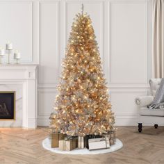 a decorated christmas tree in a living room with white walls and wood flooring, surrounded by gold wrapped presents