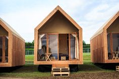 three small wooden buildings with windows on each side and one sitting in the grass outside