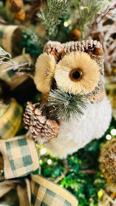 an owl ornament sitting on top of a christmas tree covered in pine cones