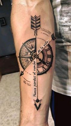 a man's arm with a compass tattoo on it and an arrow in the middle