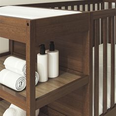 a baby crib with white towels and toiletries on the shelf next to it