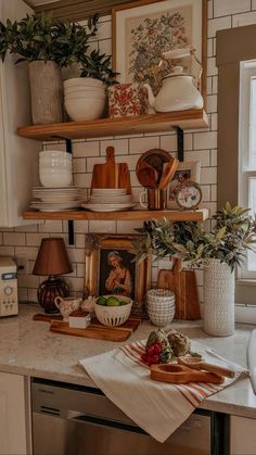 a kitchen counter with plates and bowls on top of it next to potted plants