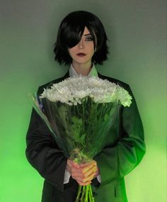 a woman holding a bouquet of flowers in front of her face and wearing a suit