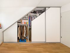 a closet under the stairs with clothes on it