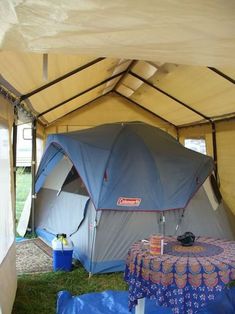 the inside of a tent that is set up on grass with tables and chairs underneath it