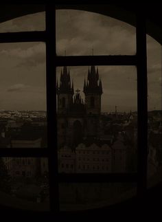 the view from an old building looking out at a city with tall buildings and spires