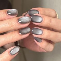 a woman's hands with grey and silver nail polishes on their fingertipss