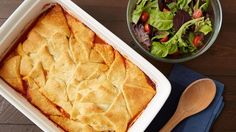 a casserole dish next to a bowl of salad