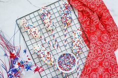 red, white and blue sprinkles are on a cooling rack next to an american flag scarf