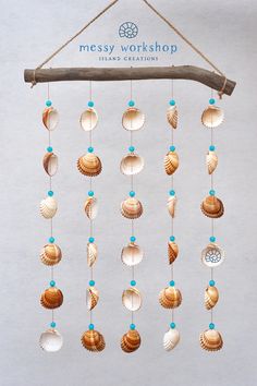 a mobile made out of shells hanging from a wooden branch with the words messy workshop on it