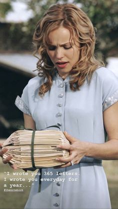 a woman holding a bunch of sticks in her hand and looking down at the pages