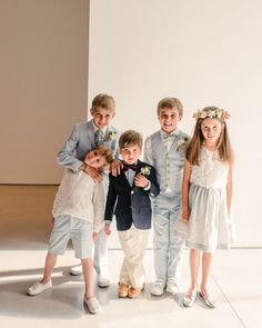 a group of young children standing next to each other in front of a white wall