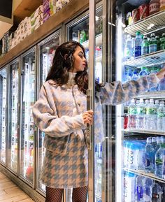 a woman standing in front of an open refrigerator filled with water and bottled drinks,