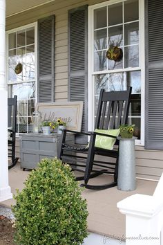 two rocking chairs on the front porch of a house with gray shutters and white trim