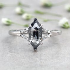 an engagement ring with a black diamond surrounded by white flowers